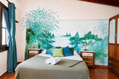 Serranía double room with turquoise wall mural of forest and lake, wooden furniture, blue pillows, and garden view in