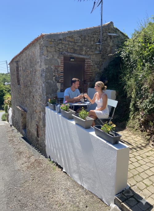 Couple savourant des verres à la terrasse en pierre rustique du gîte Le Petit Moulin à Pouzauges, France