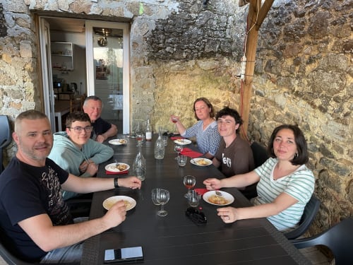 Six convives dégustent ensemble au Petit Moulin à Pouzauges, savourant leurs plats dans l'ambiance rustique des murs en pierre