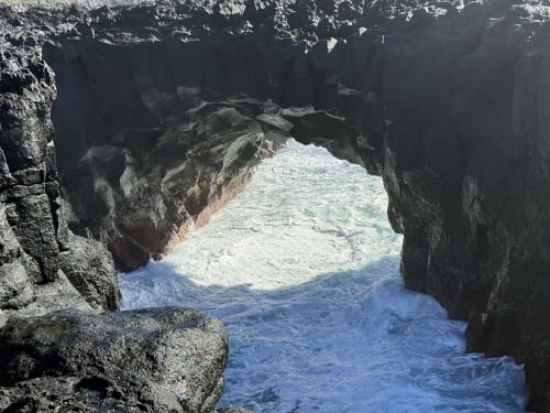 Natural rock archway framing turquoise ocean waves at Golden Mermaid Villa, Ribeirinha Portugal