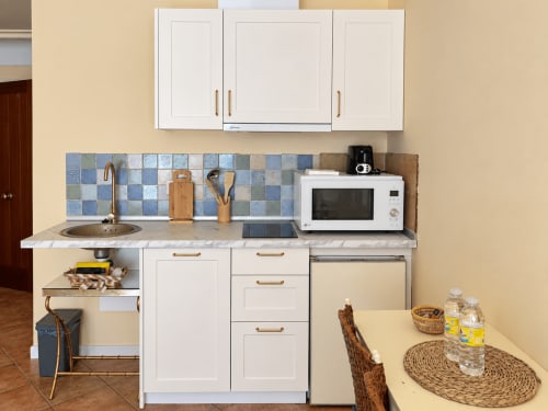 Cocina moderna en apartamento de Baiona con armarios blancos, azulejos azules, microondas y zona de comedor