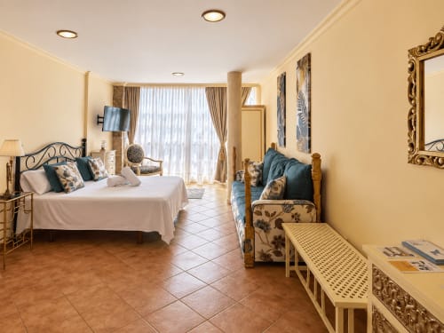 Espacioso estudio en Baiona con cama queen, zona de estar, paredes amarillas, piso de baldosas, TV de pantalla plana y balcón