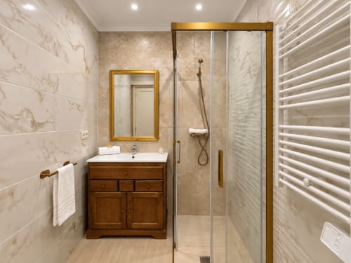 Baño moderno en apartamento Misiño, Baiona con baldosas de mármol, tocador de madera, accesorios de latón y ducha walk-in
