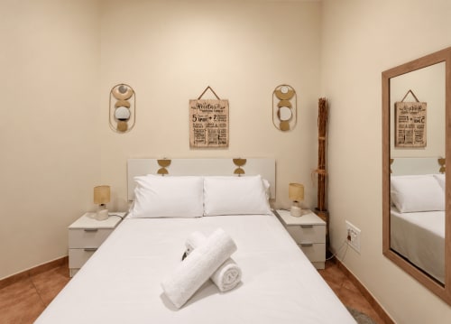 Acogedora habitación en el apartamento Holibai Ruliña de Baiona con ropa de cama blanca, detalles de madera y espejo