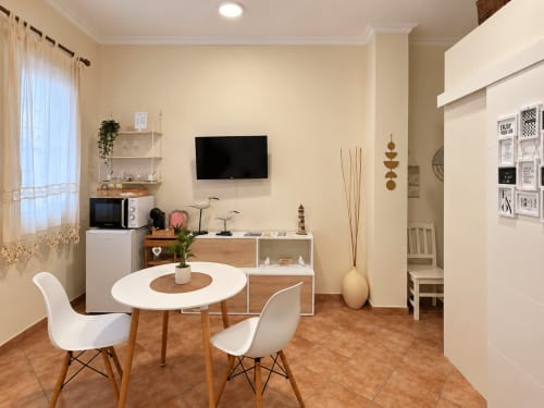 Sala de estar moderna en Baiona con mesa de comedor, TV, cocina americana y decoración contemporánea en el hotel Holibai