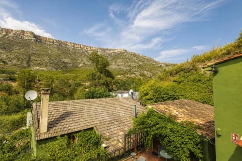 Apartment with garden view overlooking mountains in Chulilla, Spain, with ivy-covered building and tiled roofs