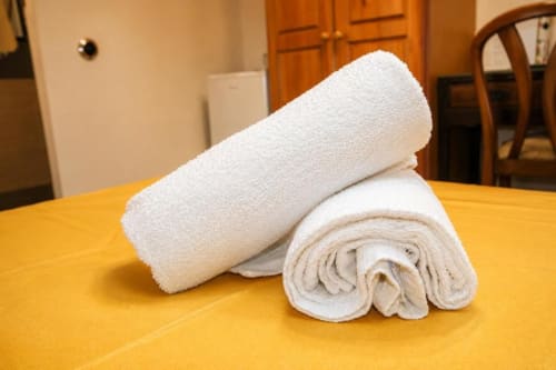 Rolled white towels displayed on a yellow table in a Chulilla hotel room with garden view decor
