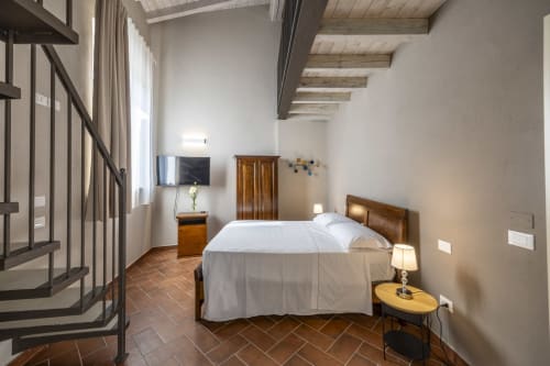Spaziosa camera da letto presso Corte Baruzzo Relais con letto matrimoniale, travi in legno, TV e vista sul giardino a Volta Mantovana