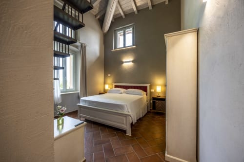 Junior Suite di Corte Baruzzo Relais a Volta Mantovana con letto bianco, pavimenti in cotto e vista sul giardino