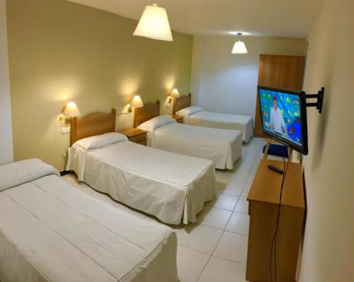 Habitación cuádruple en Hotel JM El Emigrante de Villanueva de la Serena con cuatro camas, TV de pantalla plana e iluminación cálida