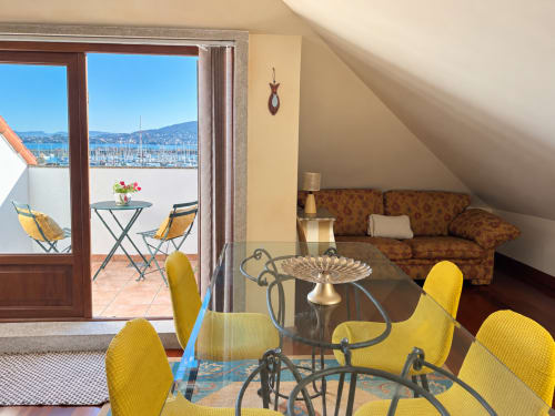 Ático de Baiona con zona de comedor, sillas amarillas, vistas al mar, marina y acceso a terraza