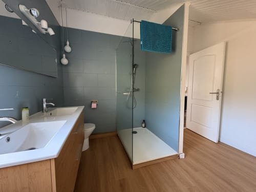 Modern bathroom with walk-in shower, dual sink vanity, and wood flooring at La Villa Maraloupia villa in Les Avirons