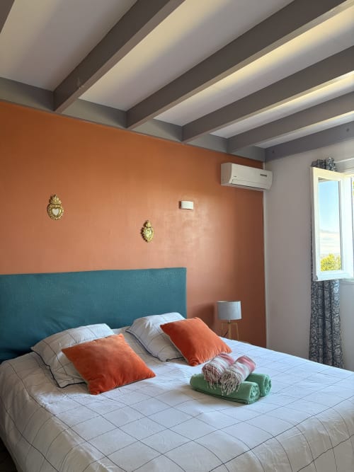 Modern bedroom at La Villa Maraloupia villa in Les Avirons with terracotta walls, teal headboard, and sea view window