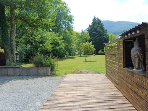 Wooden cottage deck overlooking green lawn and mountains at Le gite des mousquetaires, Lanne en Baretous