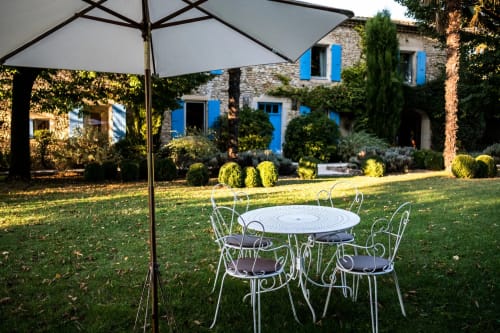 Espace de restauration en plein air aux Buis de Fontjuliane à Sauzet, mobilier blanc sous parasol dominant des jardins paysagés
