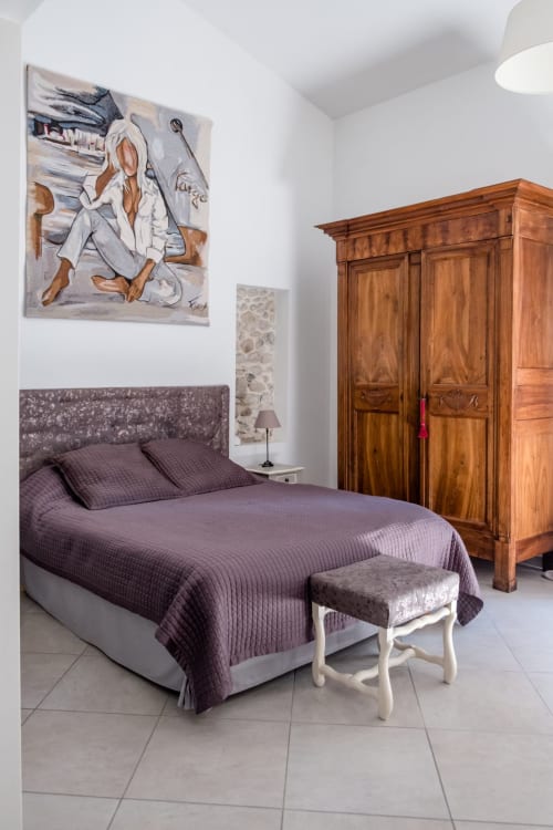 Chambre élégante des Buis de Fontjuliane à Sauzet avec literie violette, armoire en bois et œuvres d'art modernes