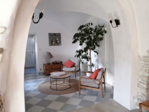 Salon lumineux aux arches chez Les buis de Fontjuliane avec chaises mi-siècle, table ronde, plante et touches rouges