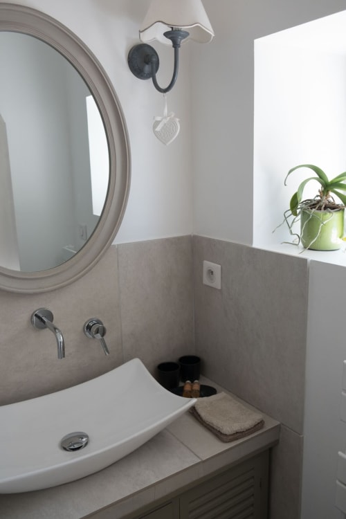Salle de bain moderne avec miroir rond, lavabo blanc et robinetterie chromée au gîte Les buis de Fontjuliane à Sauzet, France
