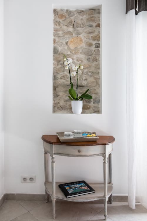 Entrée élégante avec orchidée blanche sur console face au mur de pierre brut, Les buis de Fontjuliane, Sauzet