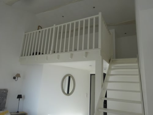 Chambre en mezzanine avec garde-corps blanc et escalier aux Buis de Fontjuliane, Sauzet