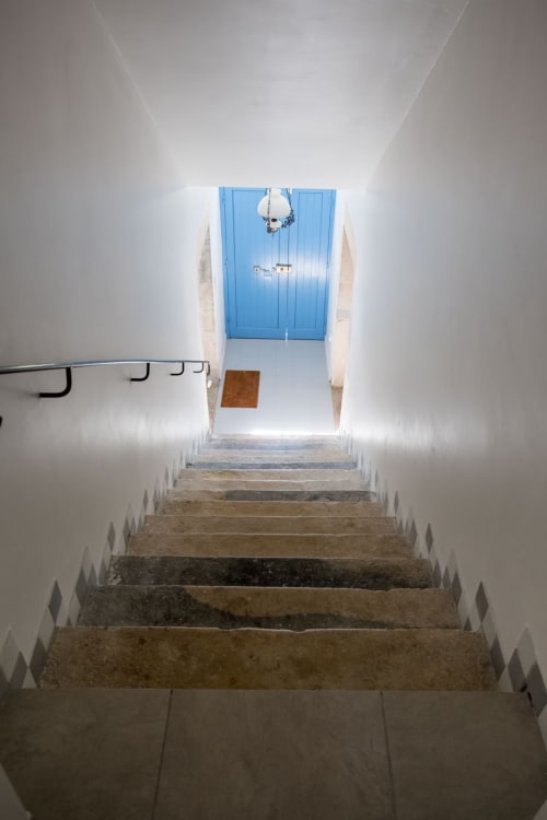 Escalier en pierre menant à une porte bleue aux Buis de Fontjulienne, gîte à Sauzet, France