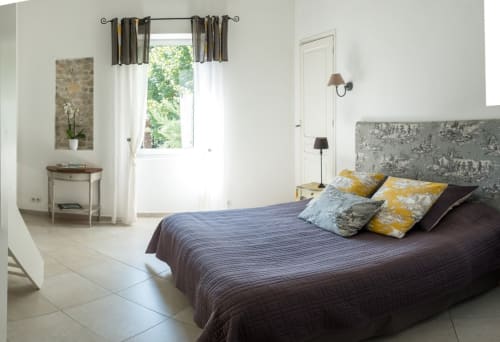 Chambre lumineuse aux Buis de Fontjuliane à Sauzet, vue sur la piscine, lit foncé, accents jaunes et décor moderne