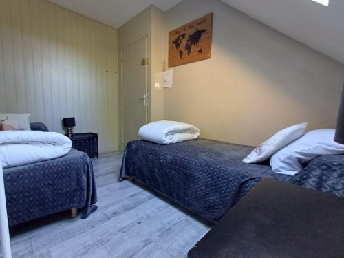 Spacious cottage bedroom at Le gite des mousquetaires in Lanne en Baretous with multiple beds, white pillows, and world map