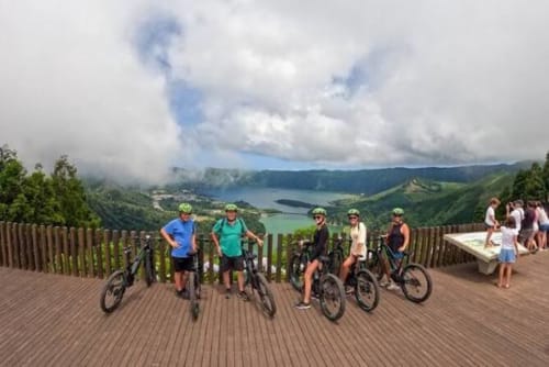 Cyclists with mountain bikes on wooden deck overlooking volcanic lake landscape at Golden Mermaid Villa, Ribeirinha Portugal