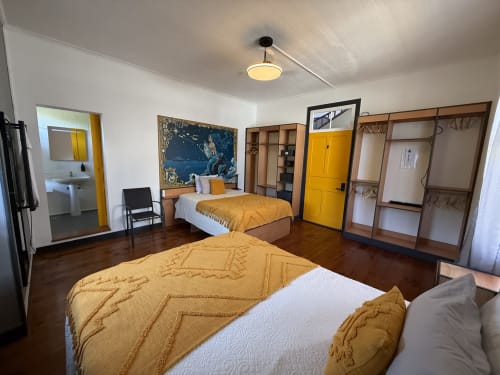 Spacious bedroom at Golden Mermaid Villa in Ribeirinha with two beds, yellow accents, wooden wardrobes, and en-suite bathroom