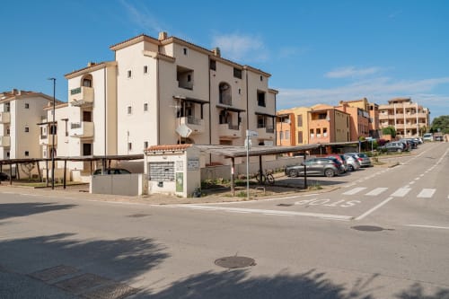 Short Let's Olbia apartment building in Sardinia with Mediterranean architecture and parking, blue sky