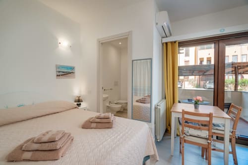 Bright studio bedroom at Short Let's Olbia with double bed, en-suite bathroom, desk, and balcony overlooking Olbia street