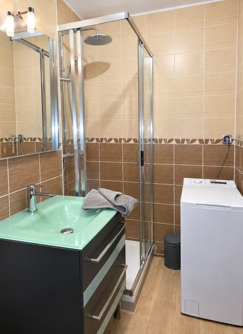 Modern bathroom in Le Cocon room at NN Patrimoine hotel, Douvaine, with green sink, glass shower enclosure, and washing