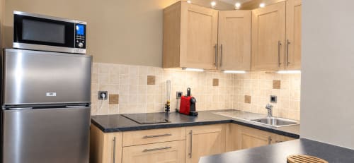 Modern kitchen in Le Cocon room at NN Patrimoine hotel, Douvaine, featuring stainless steel appliances and wooden cabinetry