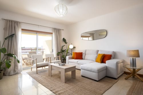 Modern living room at RB Algarve Vilamoura apartment with grey sofa, wooden furniture, and balcony views