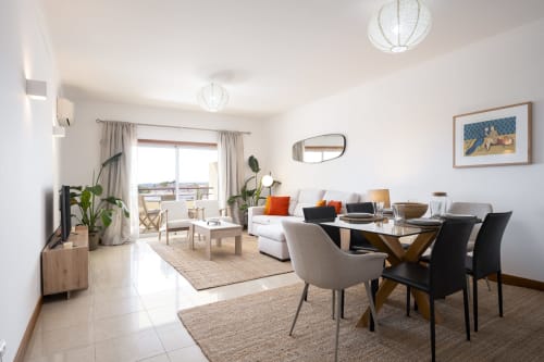 Modern apartment living room with dining area at RB Algarve Vilamoura hotel, featuring contemporary furniture and pool view