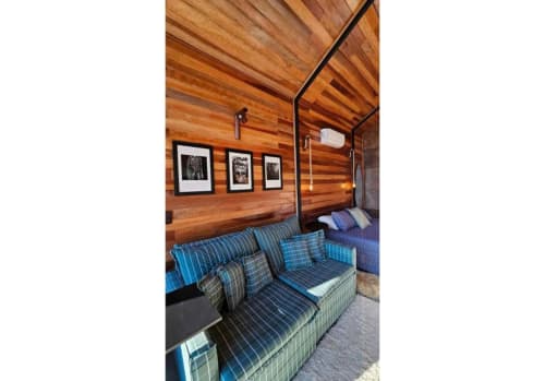 Quarto aconchegante de cabana nórdica no The Ranch Project.Co em Gonçalves com paredes de madeira, poltrona xadrez azul e obras de arte emolduradas