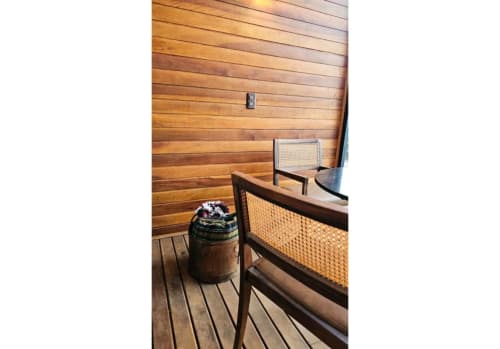 Interior da Cabana Nórdica no The Ranch Project com paredes de madeira, cadeira de rattan e cesto decorativo em Gonçalves, Brasil