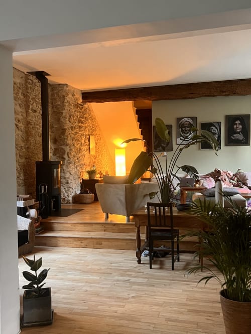 Lumière de coucher de soleil chaud dans un cottage de château restauré aux murs en pierre, poutres en bois, plantes et mobilier rustique