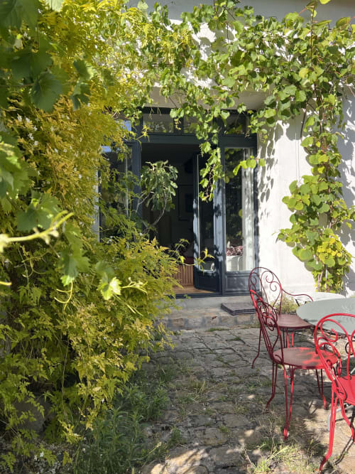 Cour verdoyante avec chaises bistro rouges aux Anciennes Écuries du Château, Boissy-Saint-Léger