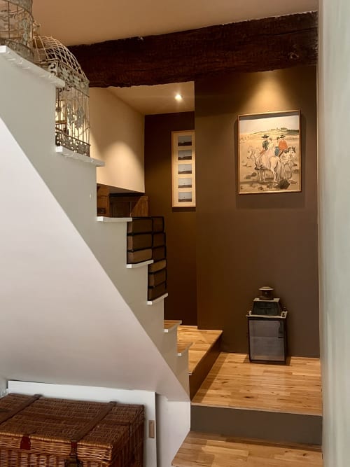 Couloir des écuries restaurées du château avec escalier en bois, poutres sombres et art western