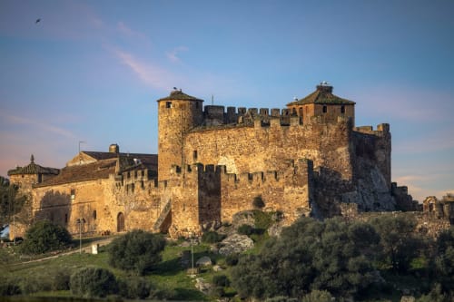 Castillo medieval con torres de piedra y fortificaciones rodeado de olivos en Villanueva de la Serena, Badajoz
