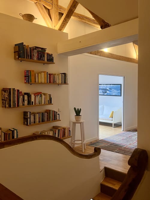 Élégante bibliothèque contemporaine aux Anciennes Écuries du Château avec mur de rayonnages courbes, puits de lumière et portes donnant sur le jardin