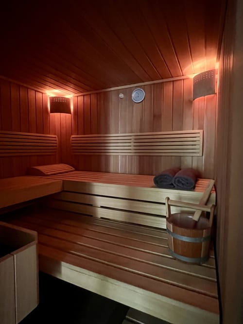 Intérieur du sauna en bois avec bancs, ambiance chaleureuse aux anciennes écuries du Château de Boissy-Saint-Léger