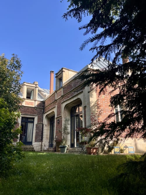 Façade de briques des anciennes écuries du Château avec jardin soigné et fenêtres cintrées à Boissy-Saint-Léger