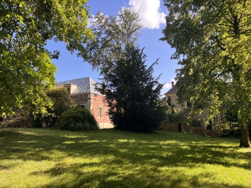 Vue depuis le jardin des Anciennes Écuries du Château, un gîte de charme à Boissy-Saint-Léger avec ses bâtiments historiques en brique