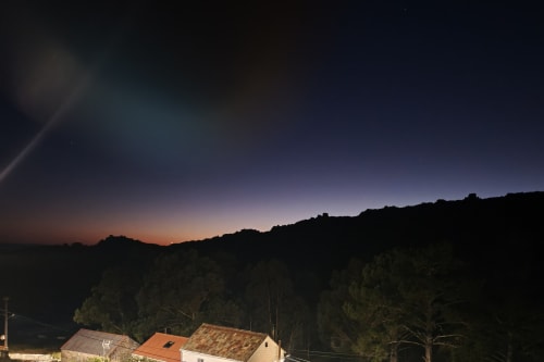 Vista crepuscular del hotel Ballenera de Caneliñas en Cee con edificios iluminados y colinas boscosas al atardecer