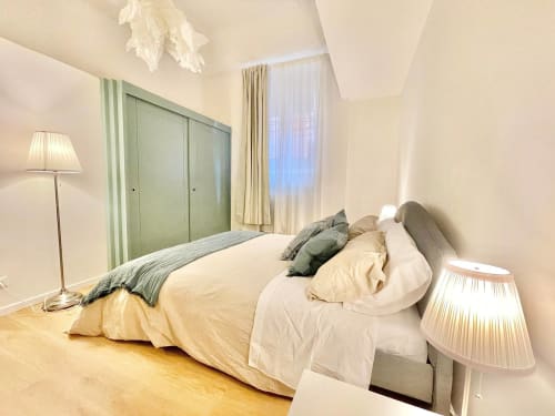 Camera luminosa nell'appartamento storico di Living Palazzi Bologna con biancheria crema, armadio verde e vista sul giardino