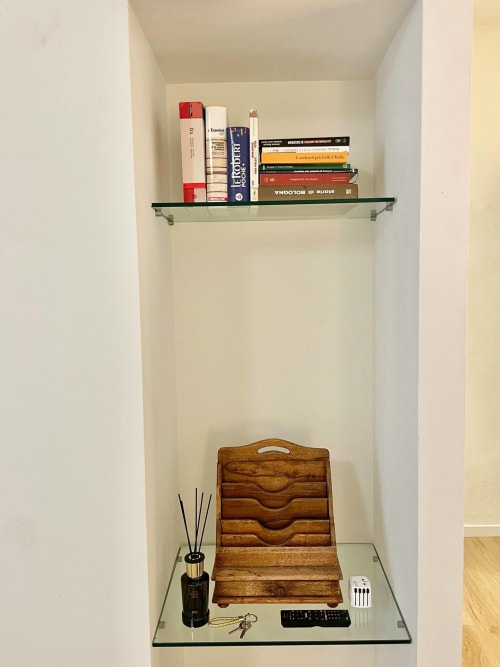 Nicchia in muratura dell'appartamento Living Palazzi Storici Bologna con libri, organizer in legno, diffusore e accessori da scrivania.