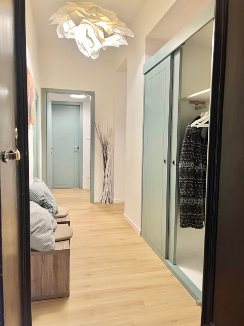 Moderno corridoio nell'appartamento di Bologna con armadio a specchio, pavimenti in legno chiaro e applique contemporanea