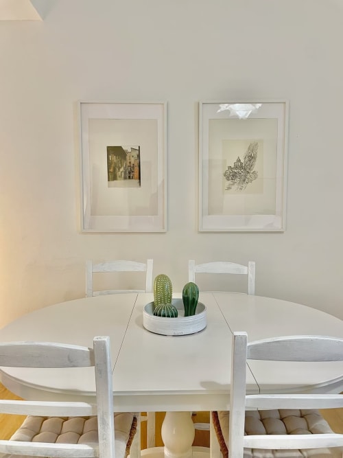 Sala da pranzo minimalista presso Living Palazzi Storici Bologna con tavolo bianco, opere d'arte incorniciate e cactus al centro.